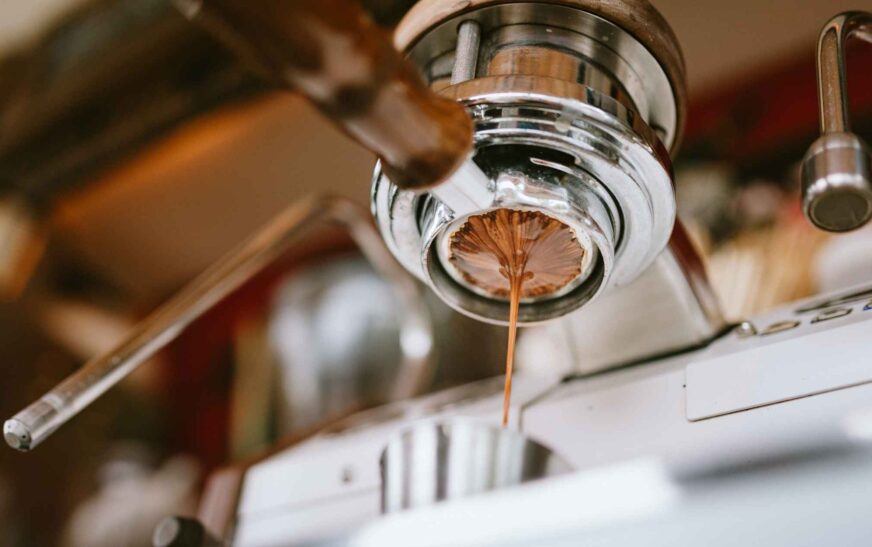 Close-up of a bottomless portafilter showing uneven coffee extraction, a common result of espresso channeling